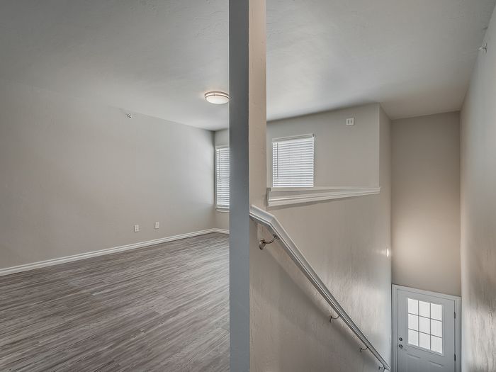 Bright interior view showing an elegant staircase leading to a spacious room with modern flooring and natural light.