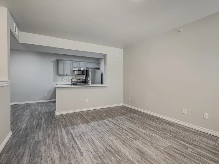 Inviting modern open-concept kitchen and living area with elegant hardwood floors and sleek gray cabinetry.