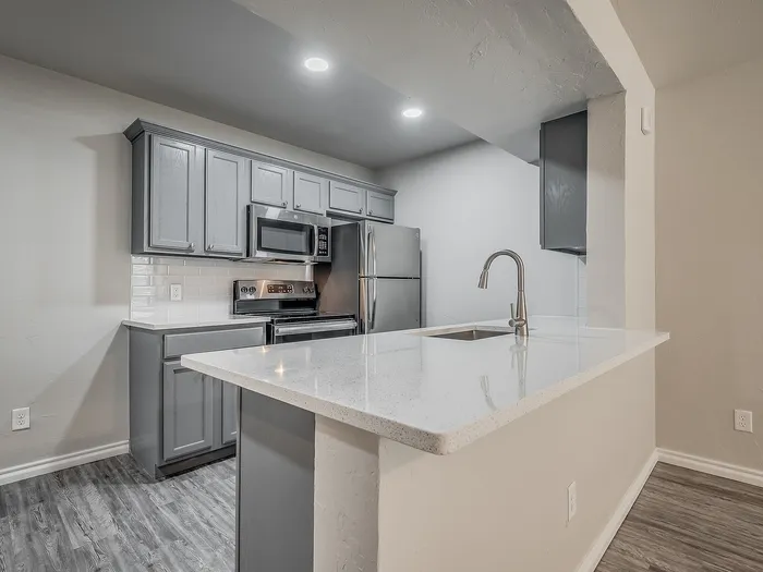 Modern kitchen with sleek gray cabinets, quartz countertops, and stainless steel appliances.