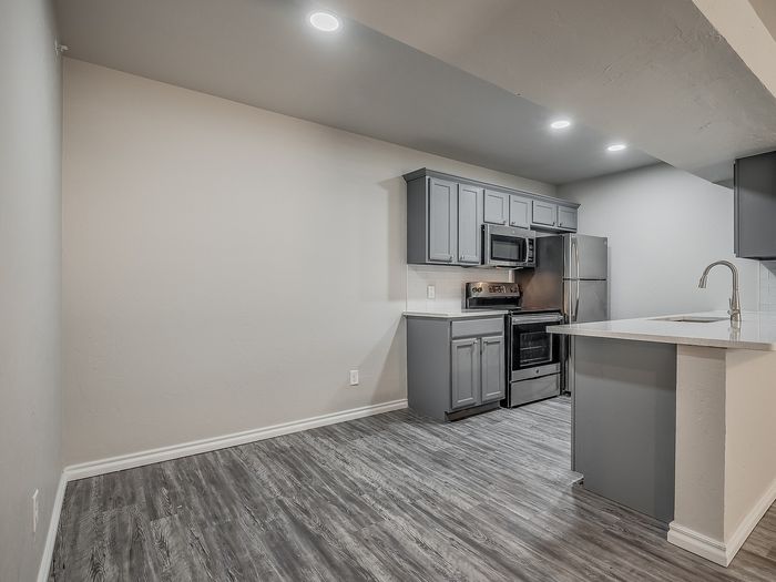 Contemporary kitchen featuring stylish gray cabinetry, sleek stainless steel appliances, and a spacious white countertop.