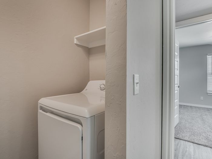 Modern laundry area featuring a sleek washing machine and convenient shelving, offering efficiency in a cozy space.