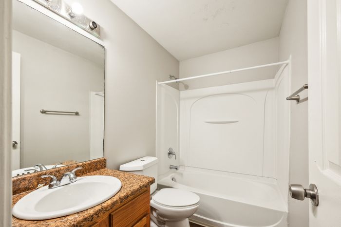 Bright and modern bathroom with granite vanity, sleek fixtures, and a spacious bathtub, perfect for relaxation.