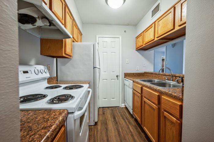 Modern galley kitchen with sleek wooden cabinets, granite countertops, and stainless steel sink, offering a functional and stylish cooking space.