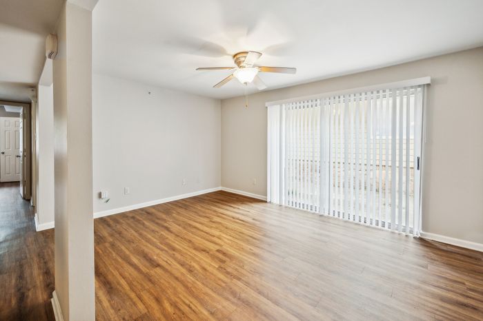 Bright, inviting living room with elegant wood flooring and plenty of natural light streaming through large sliding glass doors.