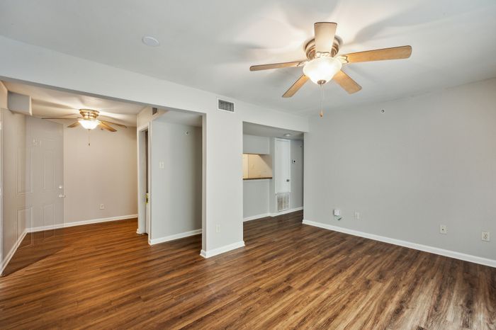 Inviting living space with sleek wood flooring, neutral walls, and stylish ceiling fans, offering a modern and comfortable atmosphere.