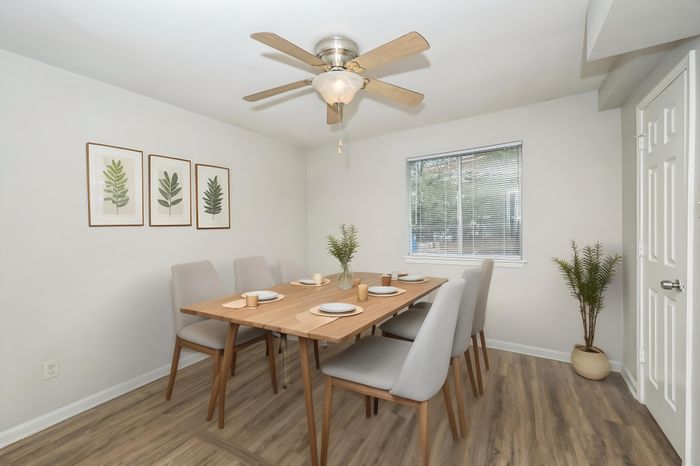 Contemporary dining room with a wooden table, elegant seating for six, and stylish botanical artwork, perfect for hosting.
