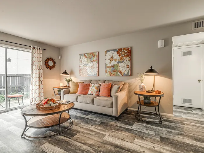 Cozy living room with stylish decor, featuring a plush sofa, chic artwork, and natural light from sliding glass doors.
