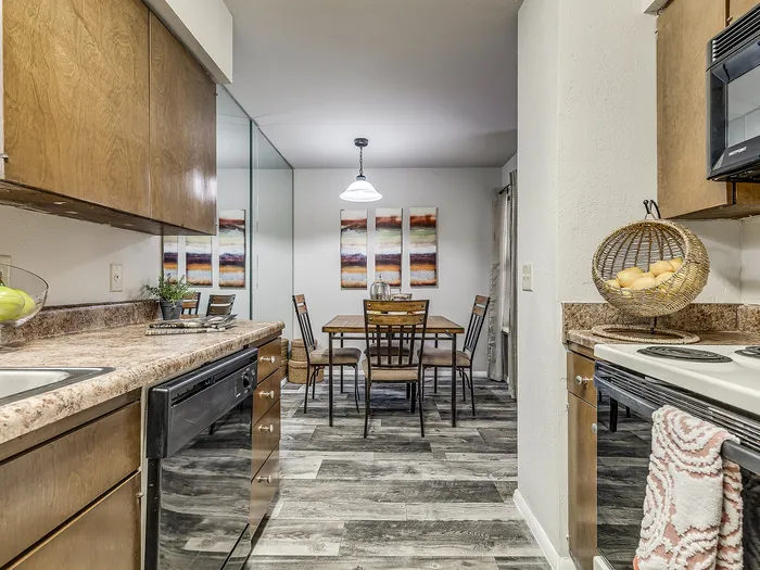 Inviting kitchen-dining area with modern appliances, wood cabinets, and elegant artwork, perfect for cozy dinners.