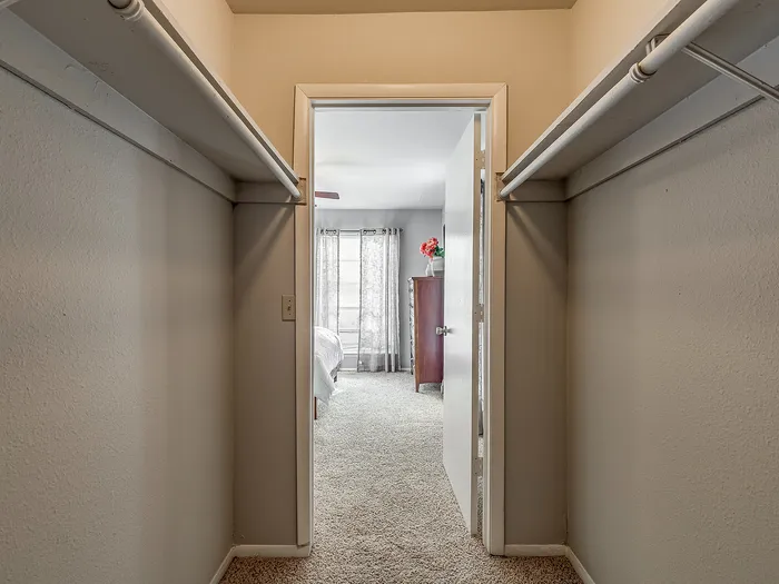 Inviting walk-in closet leading to a sunlit bedroom, perfect for a luxurious living experience.