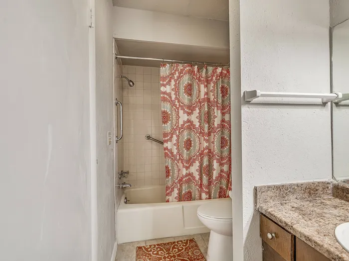 Charming bathroom with a stylish patterned shower curtain and elegant granite countertop, perfect for modern living.