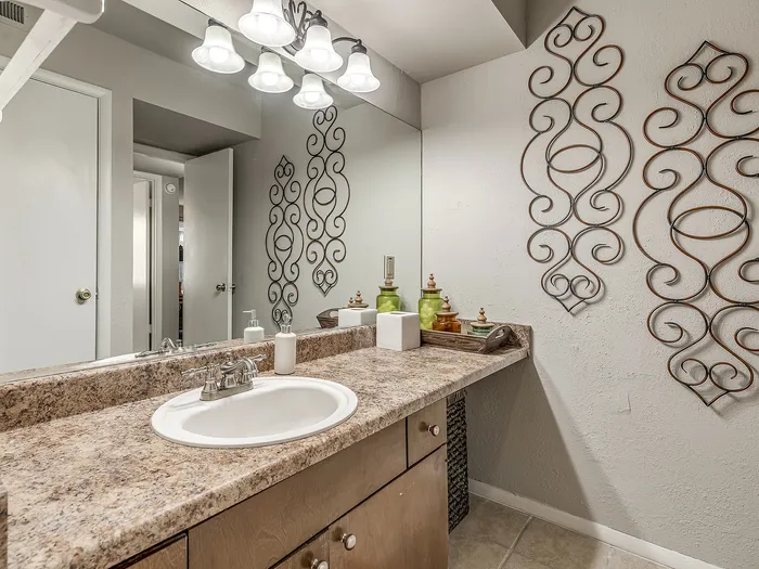 Elegant bathroom featuring a granite countertop, modern sink, and decorative wall art under ambient lighting.