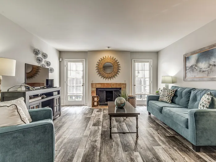 Elegant living room with modern decor, plush teal sofas, and a cozy fireplace, offering a stylish and welcoming atmosphere.