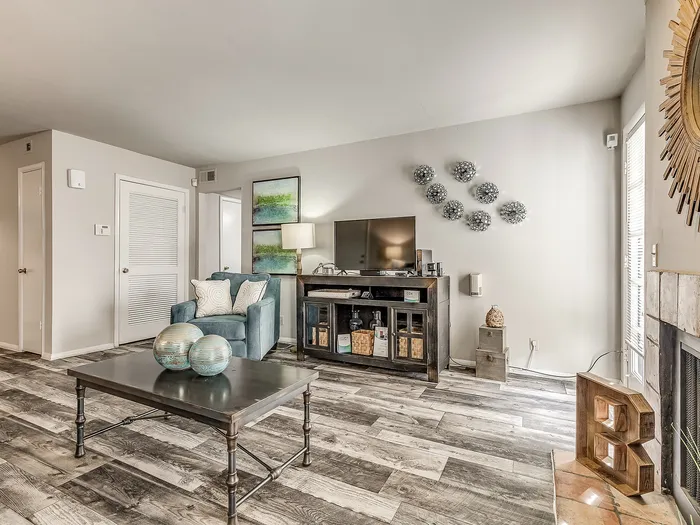 Bright and inviting living room with modern decor, featuring elegant wood flooring, a cozy armchair, and unique wall art.