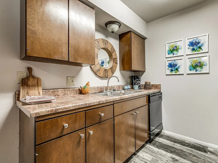 Charming kitchen with rustic wooden cabinets, modern stainless dishwasher, and elegant countertop arrangement, adorned with artistic blue flower wall decor.