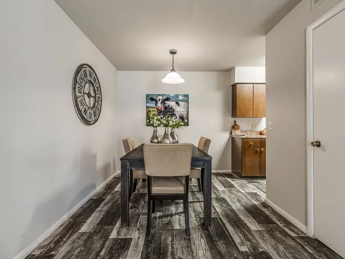 Charming dining area with rustic wooden flooring, elegant table setting, and cozy kitchen view.