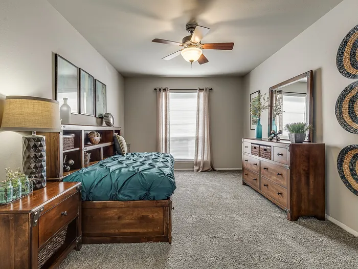 Elegant bedroom with plush carpeting, stylish wooden furniture, and a serene ambiance, featuring tasteful decor and natural light pouring in through a large window.