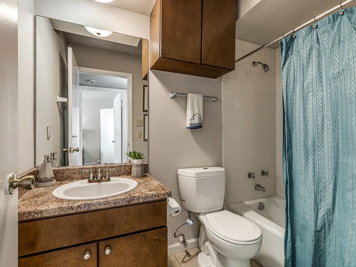 Modern bathroom featuring a sleek countertop, elegant mirror, and stylish blue shower curtain.