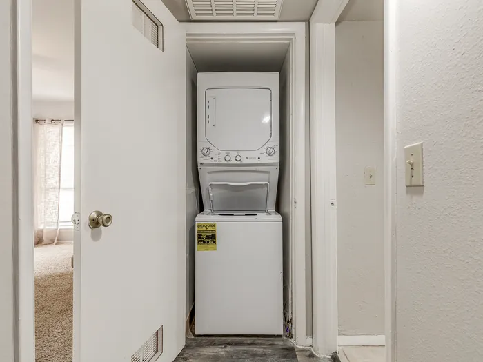Compact in-unit laundry nook with a sleek stacked washer and dryer, enhancing convenience and functionality.