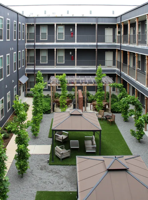 Beautiful apartment courtyard with lush greenery, modern outdoor seating areas, and stylish wooden pergolas.