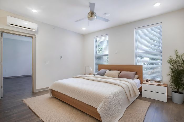 Inviting bedroom with modern wood furnishings, abundant natural light from large windows, and a cozy atmosphere accentuated by elegant decor.