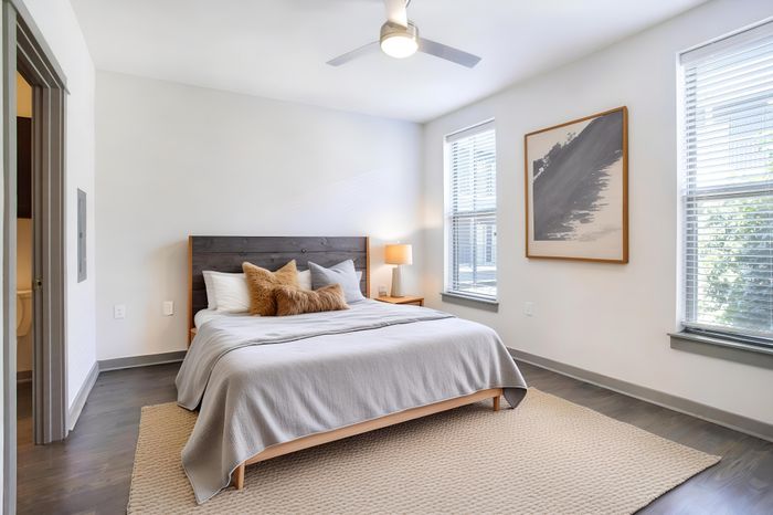 Bright and inviting bedroom with a cozy bed, modern decor, and natural light streaming through large windows.