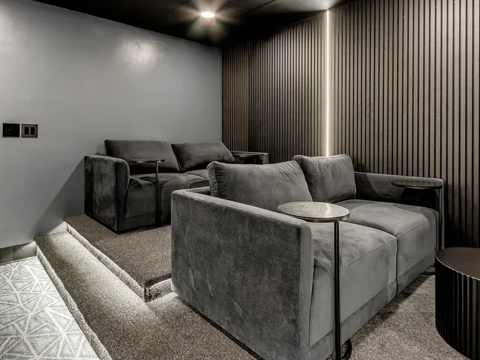 Luxurious home theater with plush gray seating and modern wall paneling.
