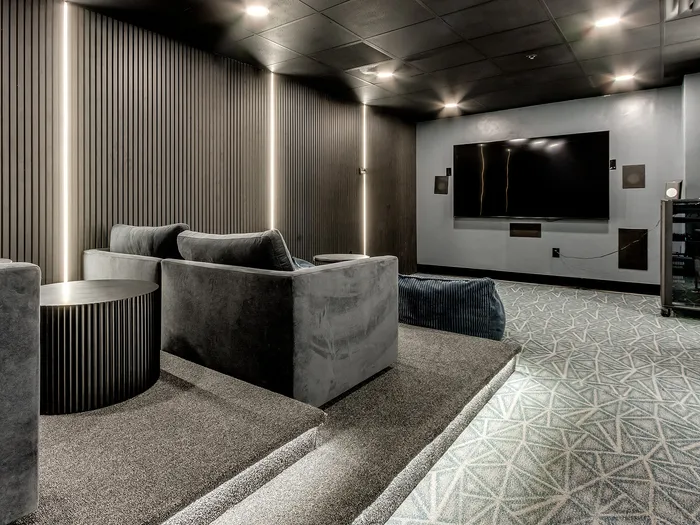Luxurious home theater room with plush grey seating, ambient lighting, and a large wall-mounted TV for an immersive entertainment experience.