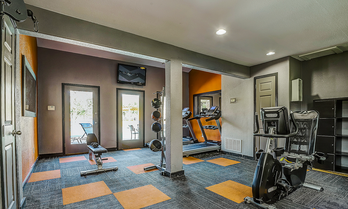 Modern fitness center with state-of-the-art equipment, vibrant orange accents, and plenty of natural light.