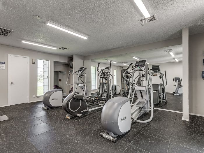 Contemporary fitness center with state-of-the-art cardio machines and mirrored walls for a bright, spacious workout area.