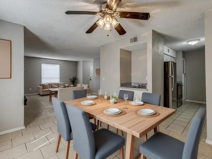 Inviting open-concept dining and living area with a modern kitchen, featuring stylish gray chairs and a wooden dining table, ideal for entertaining.