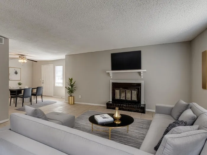 Inviting living room with modern gray sofa, elegant fireplace, and open layout leading to a chic dining area.