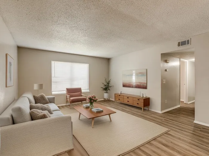 Inviting living room with modern decor, featuring a cozy sofa, stylish wooden coffee table, and elegant wall art. Bright window and sleek flooring complete the tranquil ambiance.