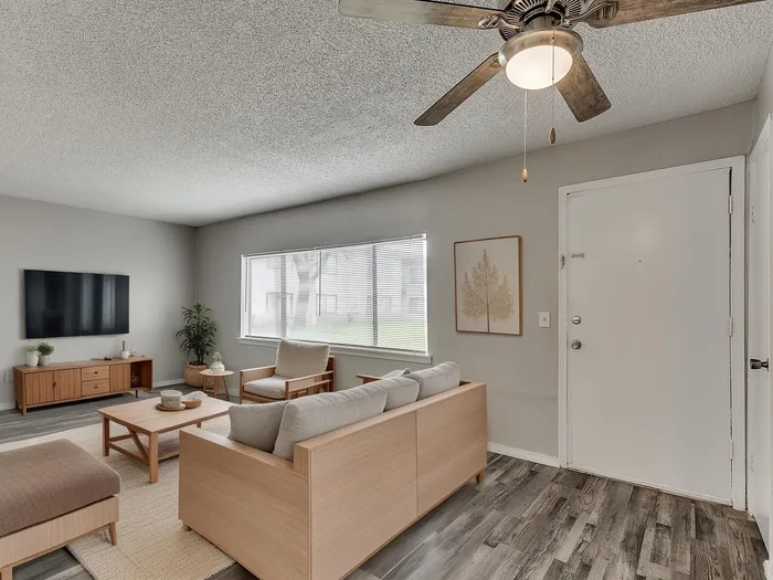 Inviting living room with modern decor, featuring a cozy seating area, wooden furniture, and a sleek mounted TV, perfect for relaxing in style.