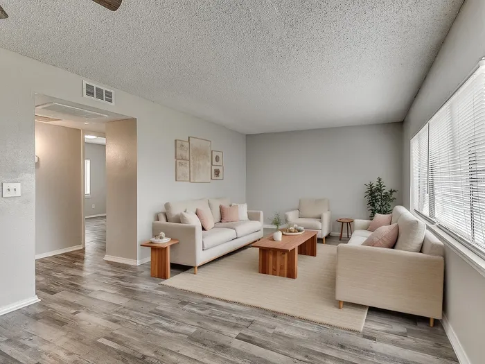 Inviting living room with stylish beige sofas, elegant wooden accents, large windows allowing natural light, and modern decor.