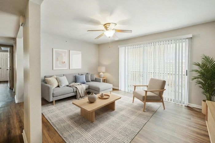 Bright and modern living room with stylish gray sofa, wood accents, and large windows letting in abundant natural light.