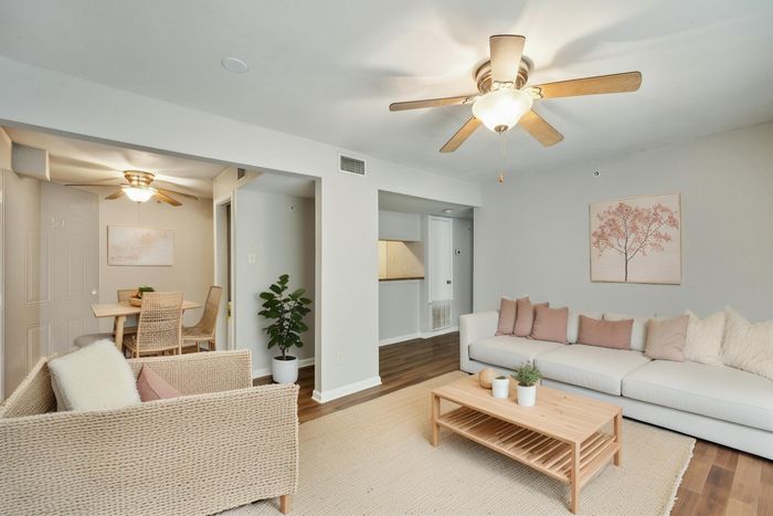 Bright and inviting living room with cozy seating and elegant decor, featuring a stylish ceiling fan and charming wall art.