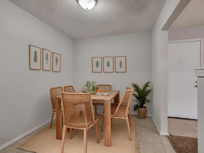 Chic dining area with a natural wood table set, elegant framed botanical art, and a cozy ambiance perfect for gatherings.