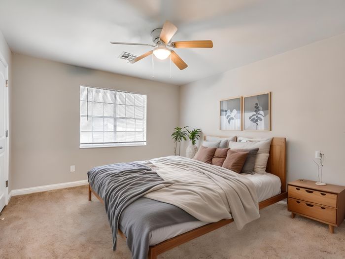 Inviting bedroom with cozy bedding, modern decor, and natural light through large window.