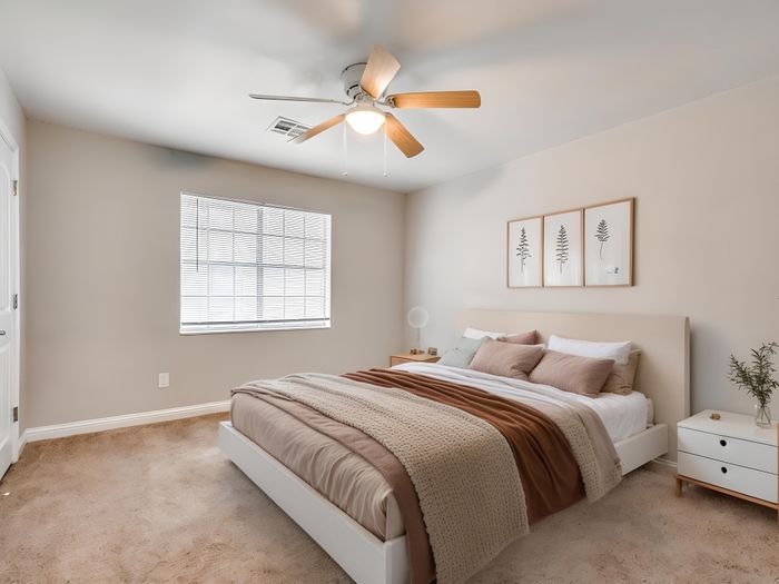 Bright and cozy bedroom with modern decor, featuring a comfortable bed, elegant ceiling fan, and soft carpeting.
