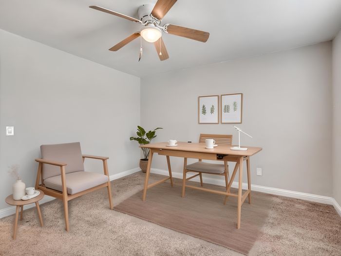 Chic home office with modern wooden furniture, cozy armchair, minimalistic decor, and leafy plant for a serene work environment.
