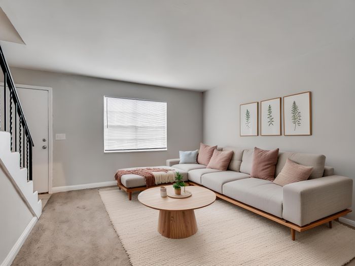 Inviting living room with modern decor, featuring a plush beige sectional sofa, elegant wall art, and abundant natural light.