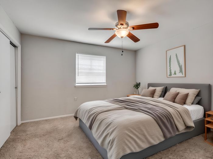 Bright and cozy bedroom featuring a comfortable double bed with plush pillows, elegant neutral decor, and a stylish ceiling fan.