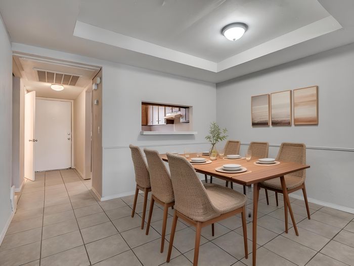 Elegant dining room featuring a modern table set for six, showcasing tasteful decor and warm lighting.