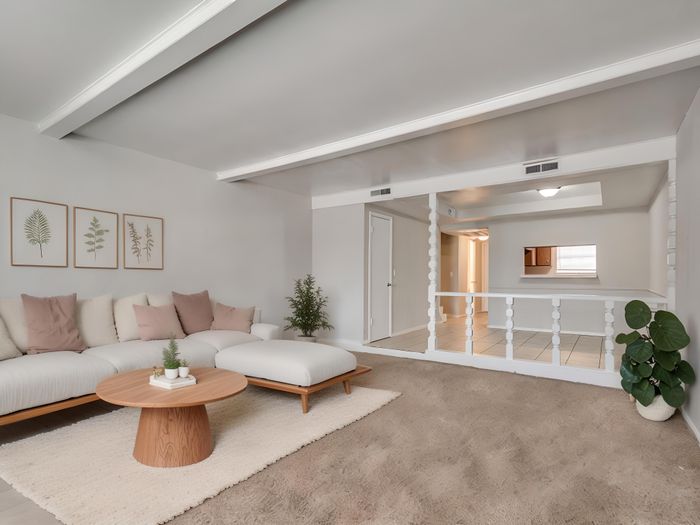 Elegant living room with a cozy white sectional sofa, stylish decor, and a modern round wooden coffee table, offering an inviting ambiance.