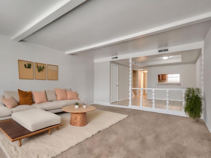 Inviting living room with modern beige sofa, plush cushions, sleek coffee table, and elegant wall art, set in a spacious, light-filled open layout.