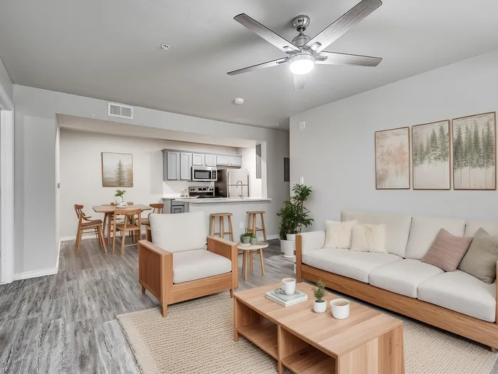 Modern and inviting living area featuring a cozy sofa, wooden coffee table, dining set, and a sleek open kitchen with stainless steel appliances.