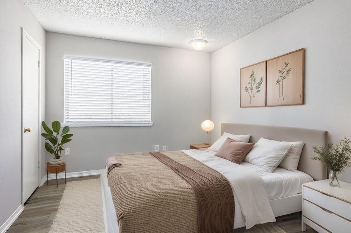 Inviting bedroom with modern decor, featuring cozy bedding, elegant wooden accents, and soft ambient lighting.