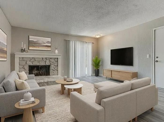 Inviting living room with a cozy stone fireplace, elegant gray sofas, and modern decor, perfect for relaxation and entertainment.