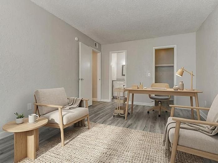 Chic apartment living space featuring modern armchairs, a stylish desk, and sleek flooring, perfect for work and relaxation.