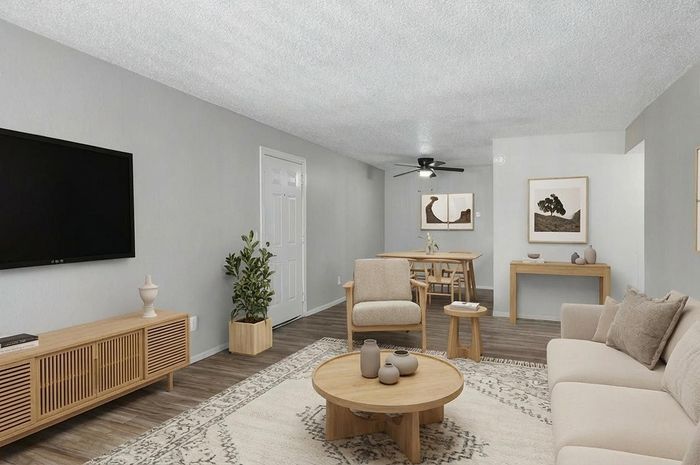 Elegant living room and dining area with modern decor, featuring a stylish beige couch, wooden furniture, and a cozy atmosphere.